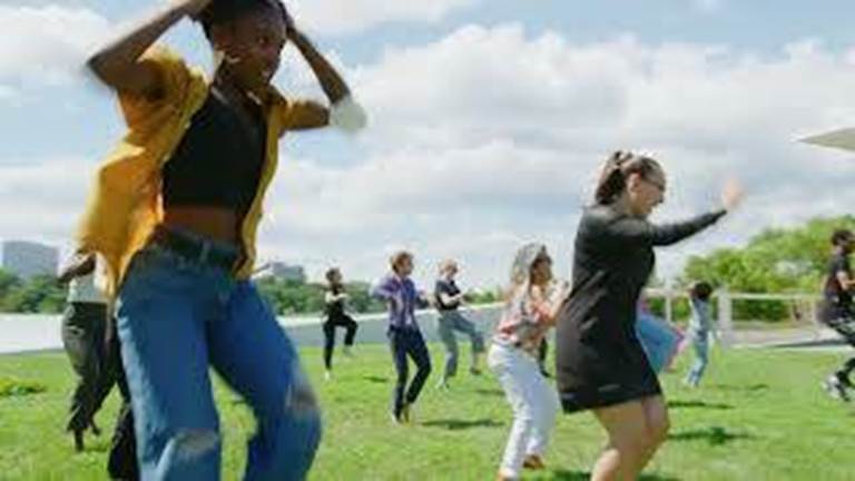 Kennedy Center Staff perform a dance move on the sunny grounds of the campus.