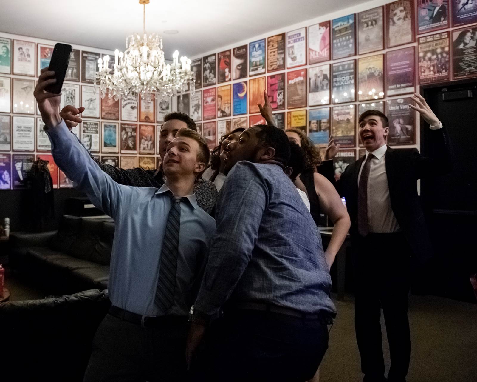 A group of students take a selfie in a room completely lined with show posters.