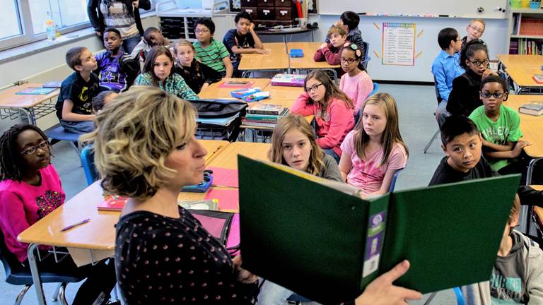 A teacher reads aloud to her classroom of students