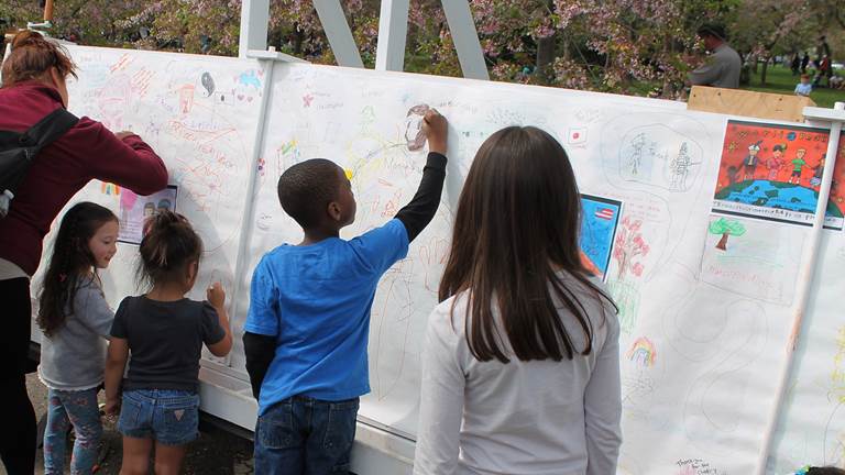 Small children and adults creating a community friendship mural. 