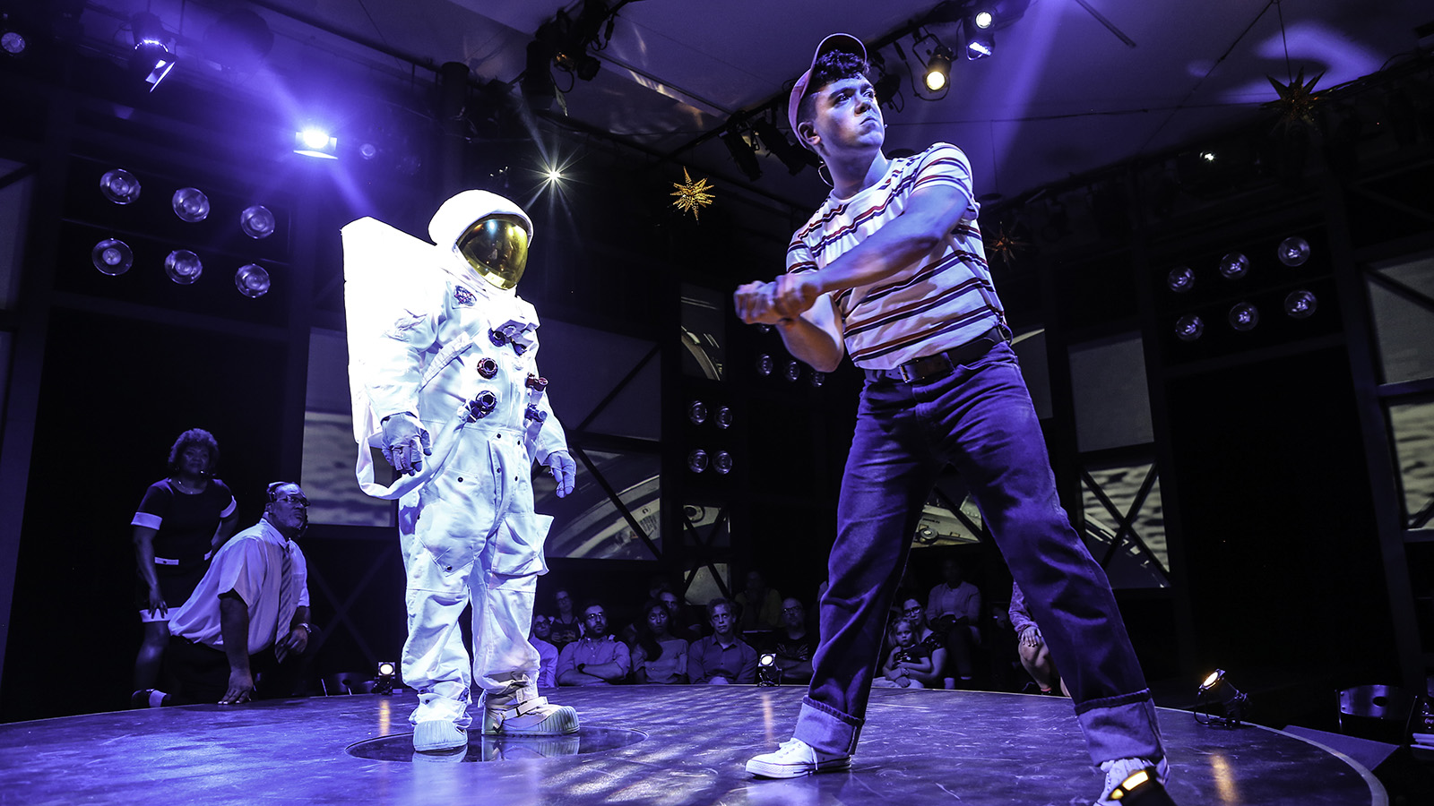 Actors dressed as an astronaut and a young person playing baseball in Earthrise