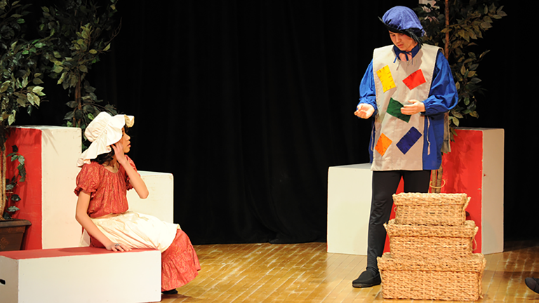 Two actors on a stage performing a scene from a play.