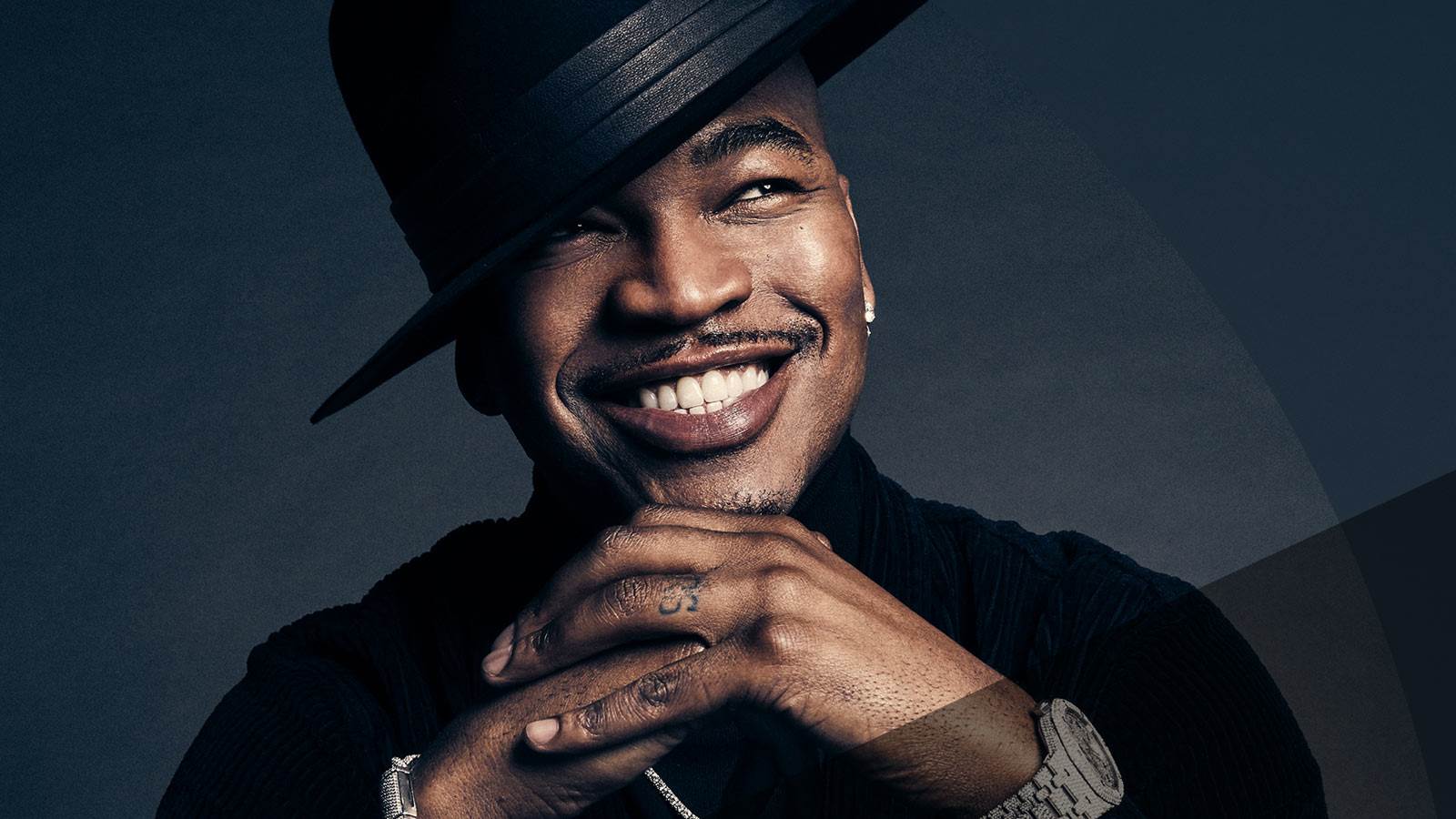 Ne-Yo smiling with black hat tipped to the side