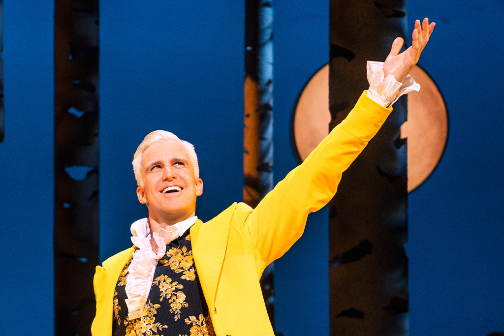 Gavin Creel in Into the Woods reaching hand into sky wearing yellow jacket